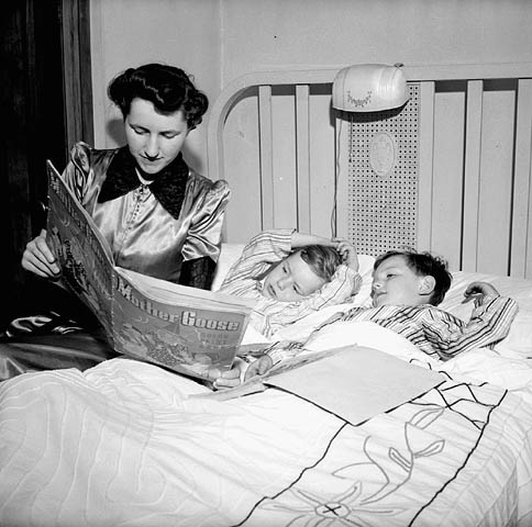 À l'heure du coucher Mme Jack Wright lit une histoire à ses deux fils, Ralph et David, 1943 (Office national du film du Canada. Photothèque. Bibliothèque et Archives Canada)